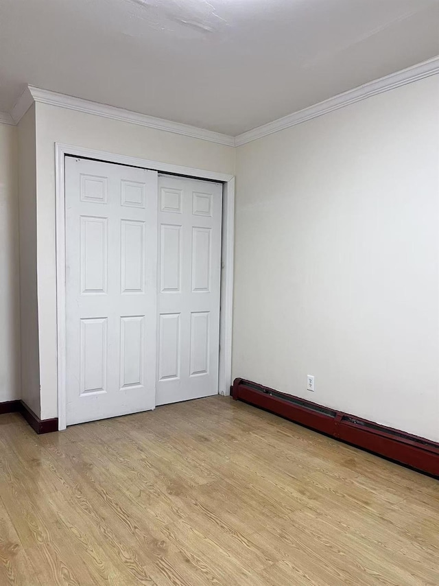 unfurnished bedroom with ornamental molding, light hardwood / wood-style floors, a closet, and a baseboard radiator