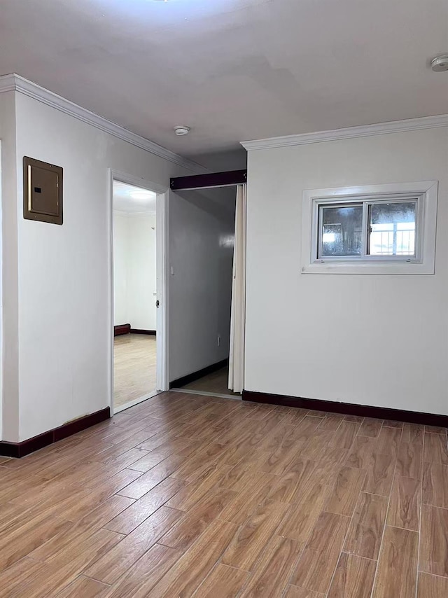 spare room featuring electric panel, crown molding, and light hardwood / wood-style flooring