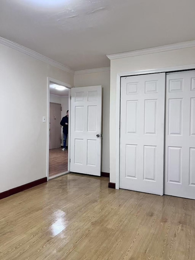 unfurnished bedroom featuring a closet, light hardwood / wood-style floors, and crown molding