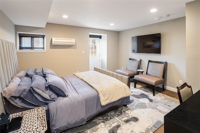 bedroom featuring an AC wall unit, wood-type flooring, and multiple windows