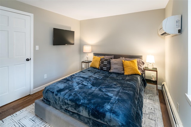 bedroom with a baseboard heating unit, a wall mounted AC, and hardwood / wood-style flooring