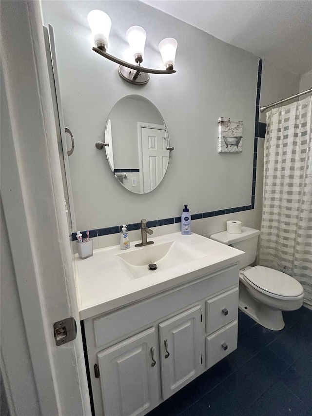 bathroom with tile patterned floors, toilet, vanity, and tile walls