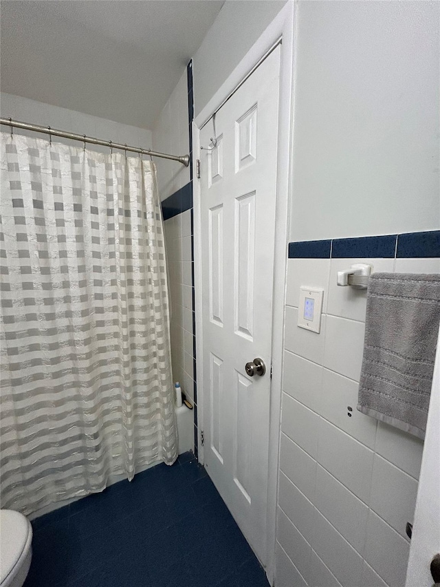 bathroom with tile walls, shower / bathtub combination with curtain, and toilet