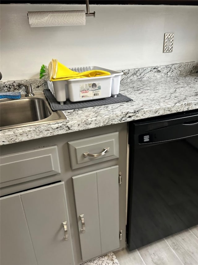 kitchen featuring gray cabinets, black dishwasher, light stone counters, and light hardwood / wood-style floors