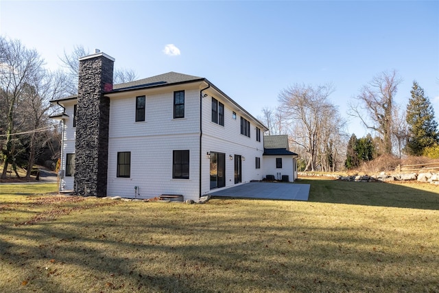 back of property with a lawn and a patio