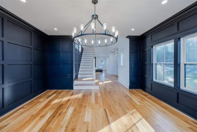 unfurnished dining area with ornamental molding, light hardwood / wood-style flooring, and a notable chandelier