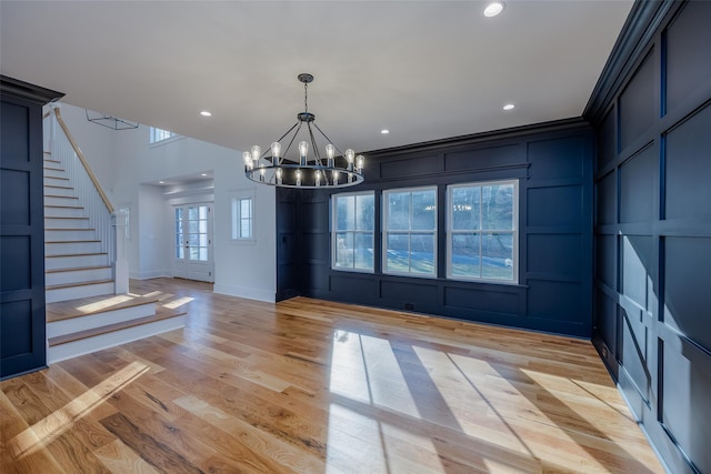 unfurnished dining area featuring a chandelier, light hardwood / wood-style floors, and ornamental molding