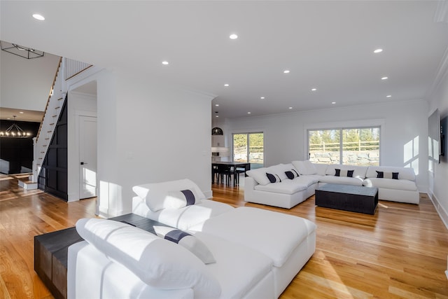 living room featuring light hardwood / wood-style flooring, ornamental molding, and a notable chandelier