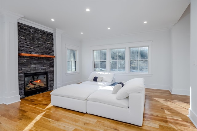 living room with light wood-type flooring, ornamental molding, and a fireplace