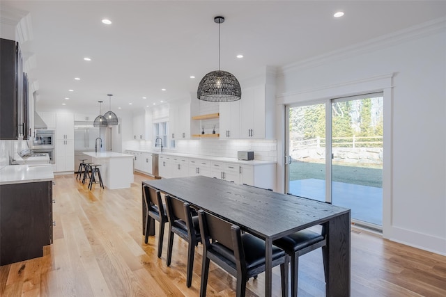 dining area featuring sink, ornamental molding, and light hardwood / wood-style floors