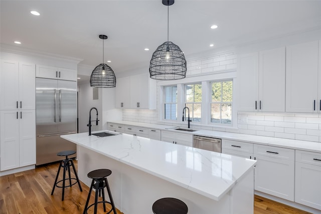 kitchen featuring white cabinets, sink, an island with sink, and stainless steel appliances