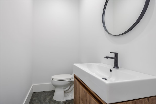 bathroom with toilet, vanity, and tile patterned flooring