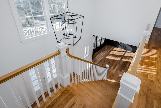 stairway with hardwood / wood-style floors and a notable chandelier