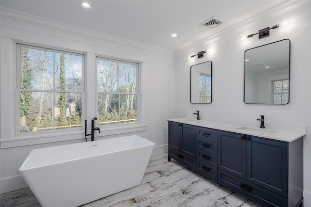 bathroom featuring a tub to relax in, vanity, and crown molding