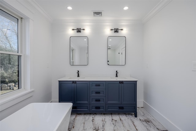 bathroom with hardwood / wood-style flooring, a bath, ornamental molding, and vanity