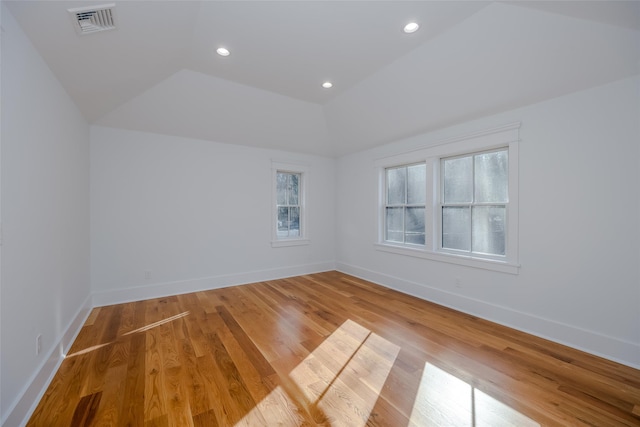 spare room featuring hardwood / wood-style floors and vaulted ceiling