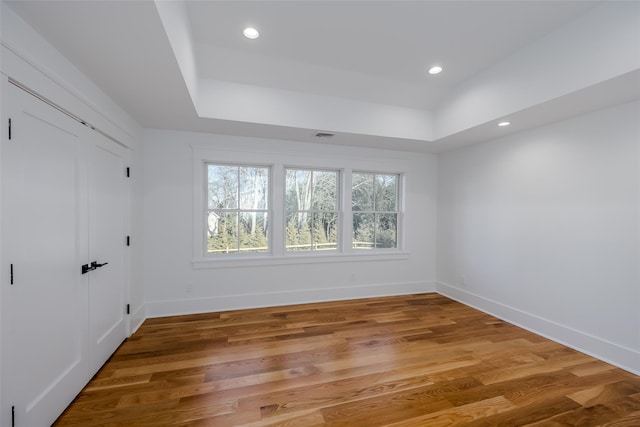 unfurnished room featuring hardwood / wood-style floors and a tray ceiling