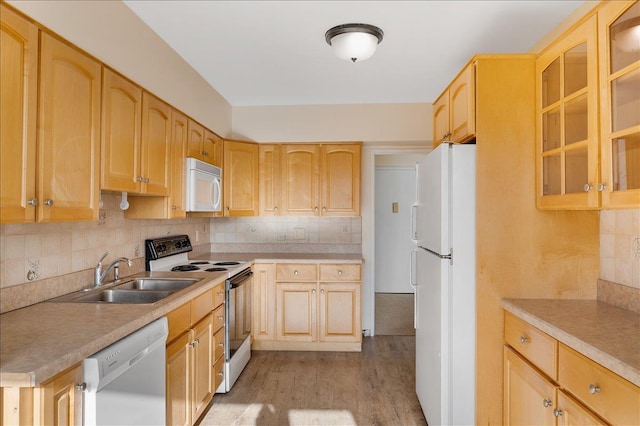 kitchen with light brown cabinetry, sink, white appliances, and backsplash