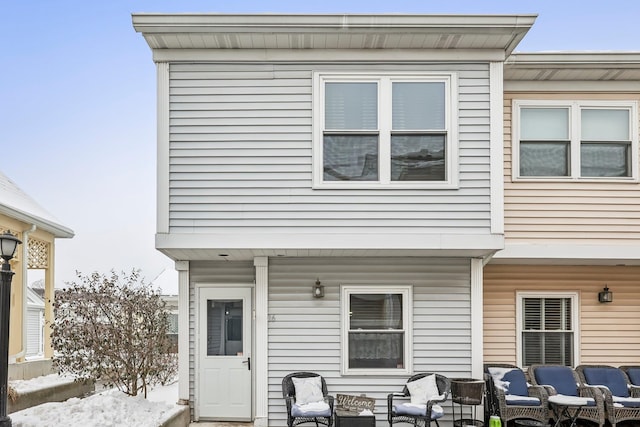 snow covered back of property with an outdoor living space and a patio area