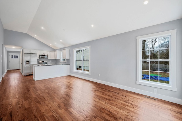 unfurnished living room featuring lofted ceiling, wood-type flooring, and sink