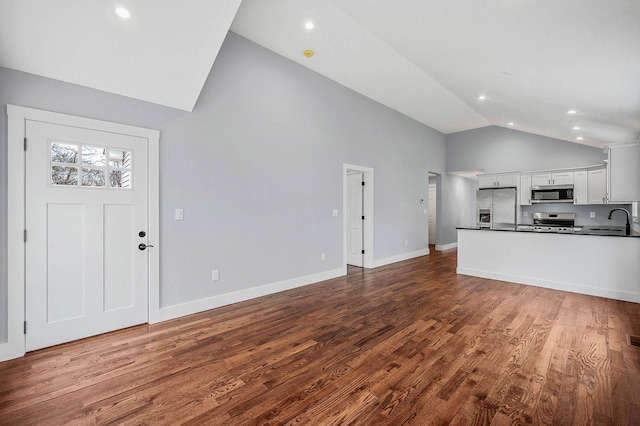 unfurnished living room featuring high vaulted ceiling, sink, and wood-type flooring