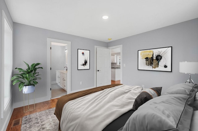 bedroom with ensuite bath and hardwood / wood-style flooring