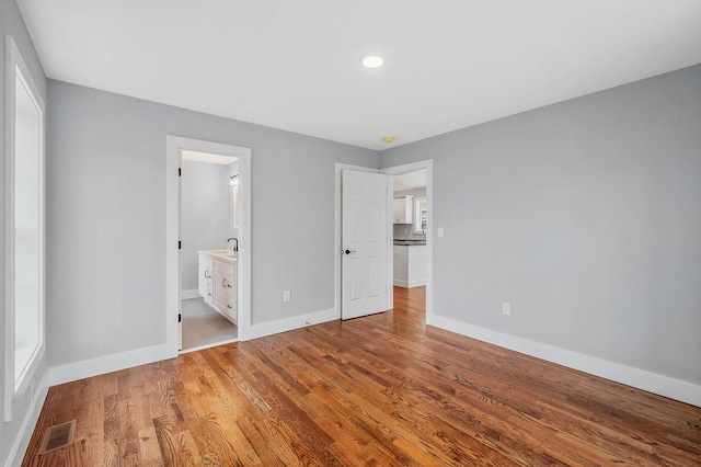 unfurnished bedroom with sink, light hardwood / wood-style flooring, and ensuite bath