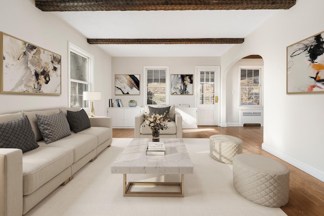 living room with radiator heating unit, hardwood / wood-style flooring, and beam ceiling