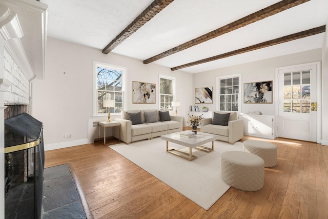 living room with a brick fireplace, hardwood / wood-style floors, and beamed ceiling