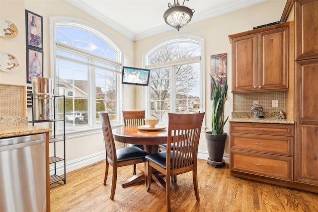 dining room featuring a notable chandelier, light wood-type flooring, a wealth of natural light, and crown molding