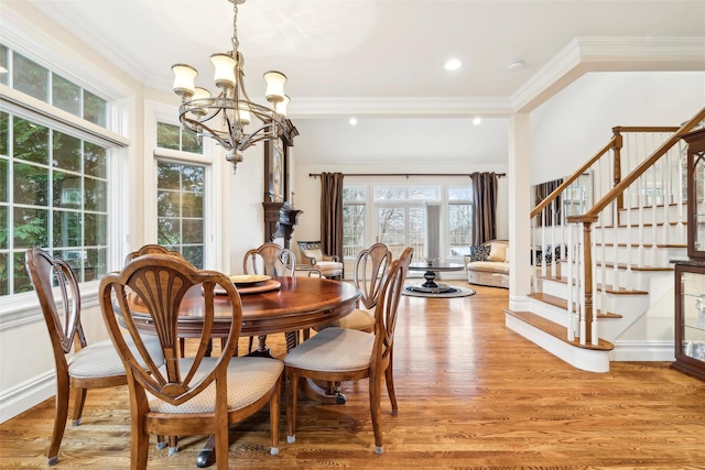 dining space with light hardwood / wood-style floors, an inviting chandelier, and ornamental molding