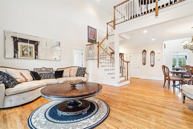 living room with ornamental molding, a towering ceiling, a chandelier, and wood-type flooring