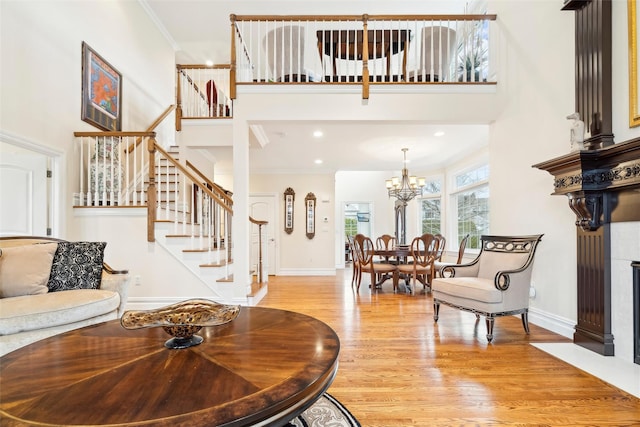 foyer entrance with a high ceiling, an inviting chandelier, light wood-type flooring, and crown molding