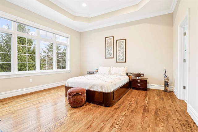 bedroom featuring light hardwood / wood-style floors, crown molding, and a raised ceiling