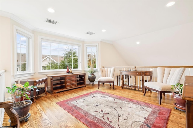 living area with ornamental molding, light wood-type flooring, and vaulted ceiling