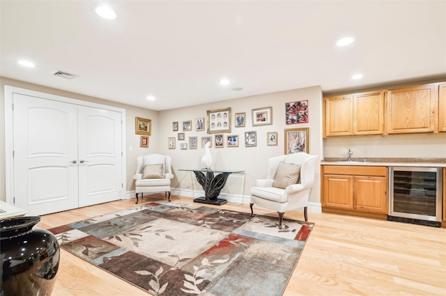 interior space featuring indoor wet bar, beverage cooler, and light hardwood / wood-style flooring