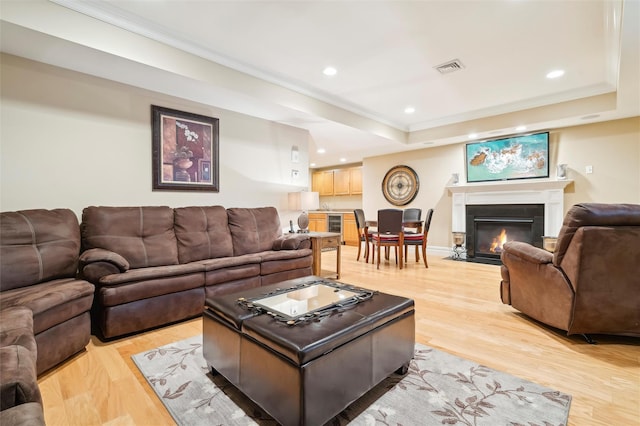 living room with beverage cooler, light wood-type flooring, and a tray ceiling