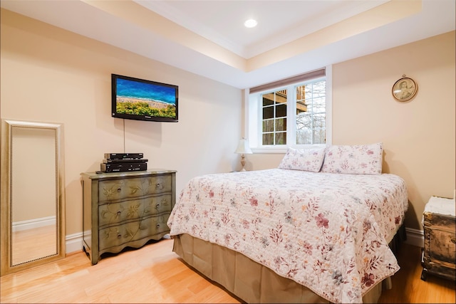 bedroom featuring a raised ceiling and light wood-type flooring