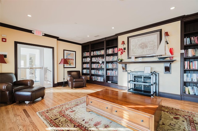 sitting room featuring hardwood / wood-style flooring, built in features, and ornamental molding