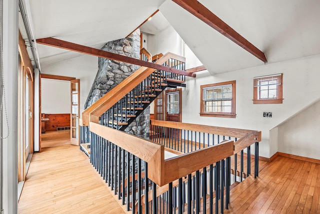 staircase with wood-type flooring and lofted ceiling with beams