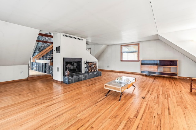 living room with a fireplace, wood-type flooring, and vaulted ceiling