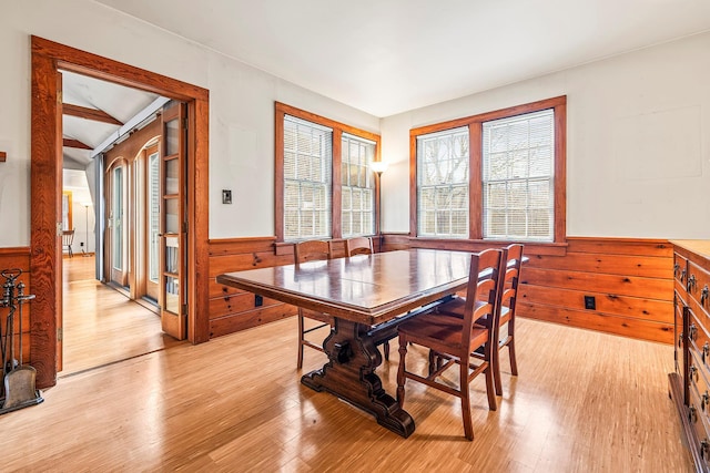 dining space with wood walls and light wood-type flooring