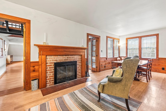 living room with wooden walls, a brick fireplace, and light hardwood / wood-style flooring