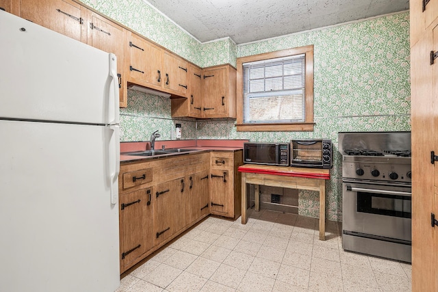 kitchen featuring white refrigerator, gas range, and sink