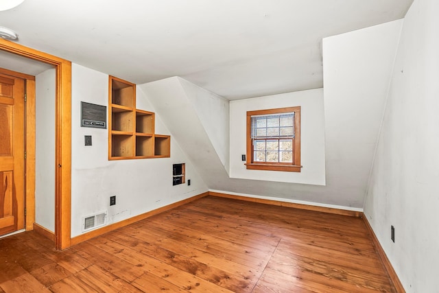 additional living space with hardwood / wood-style floors and built in shelves