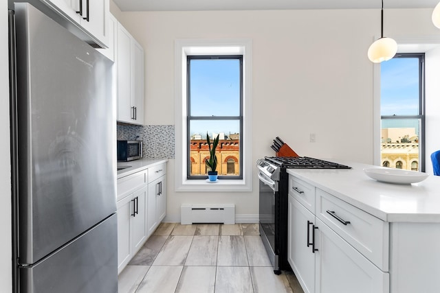 kitchen with decorative light fixtures, tasteful backsplash, a baseboard heating unit, appliances with stainless steel finishes, and white cabinets