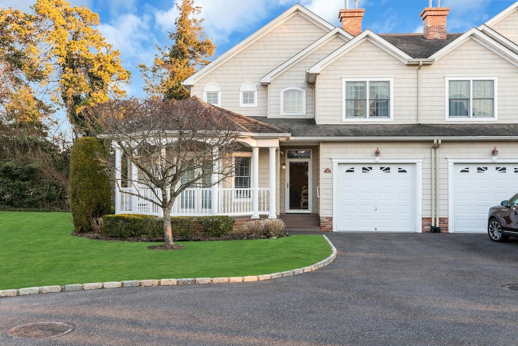 view of front of home with a front lawn, covered porch, and a garage