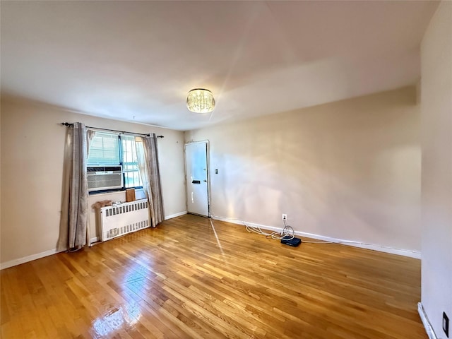 spare room with wood-type flooring, cooling unit, a chandelier, and radiator