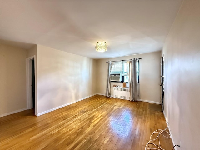 empty room with light hardwood / wood-style flooring and radiator heating unit