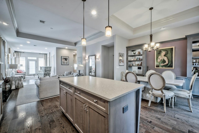 kitchen featuring a kitchen island, a tray ceiling, hanging light fixtures, and dark hardwood / wood-style floors